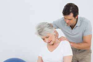 Chiropractor rubbing neck of senior female patient