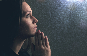 a-woman-holds-her-hands-in-prayer-during-a-rain-storm_0.jpg