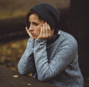 depressed woman sitting at a picnic table in the woods