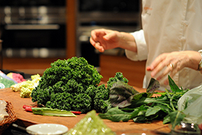 Close up of a chef's hands preparing leafy greens