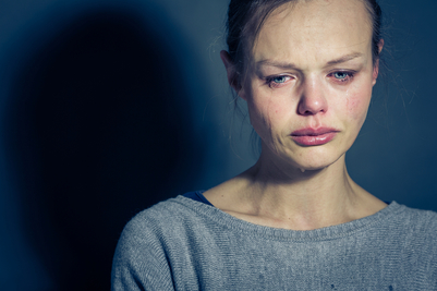 anxious woman crying in front of a blue background