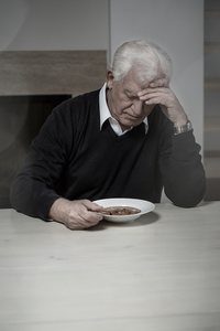 lonely older man eating soup alone