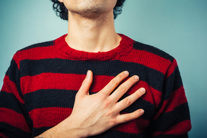 close up of man's torso, wearing a striped sweater. his hand is over his heart