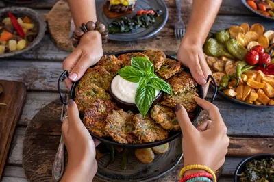 two people holding a bowl of vegetable fritters