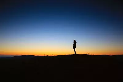a lone silhouette standing in front of a sunset