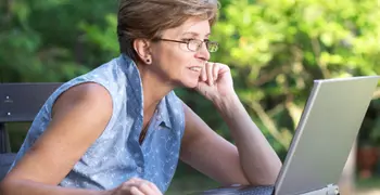 middle aged woman using laptop outside