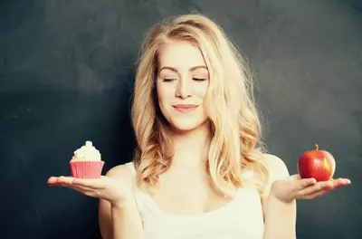 woman choosing between cupcake and apple