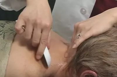 hands spreading hot oil on a patient's neck