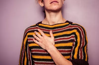 woman in colorful sweater with her hand on her chest