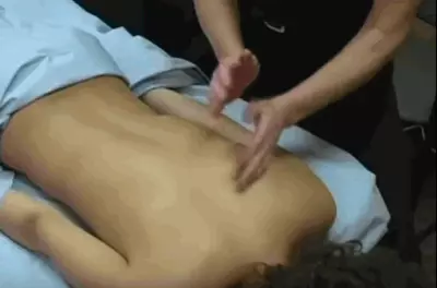 Masseuse's hands tapping against a client's bare back