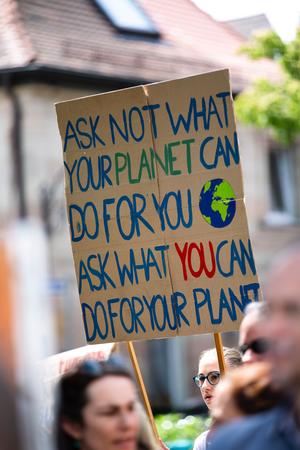person in crowd holding sign that says ask not what your planet can do for you, ask what you can do for your planet