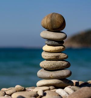 eight flat stones stacked on top of one another on the edge of a body of water