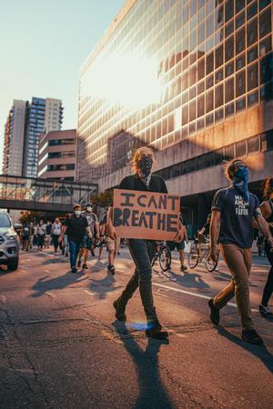 people protesting on a street carrying a sign that says I Can't Breathe