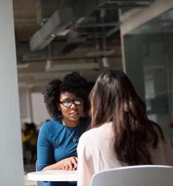 two women sitting at a table talking