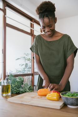 smiling woman cutting vegetables in her kitchen