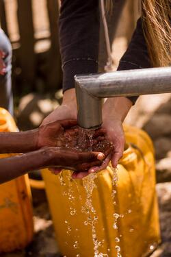 hands washing over a spigot