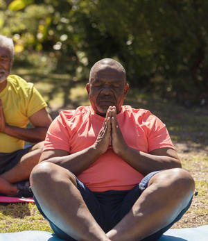 elderly man with legs folded in yoga pose and eyes closed