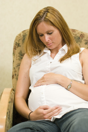 pregnant woman with white shirt sitting on couch