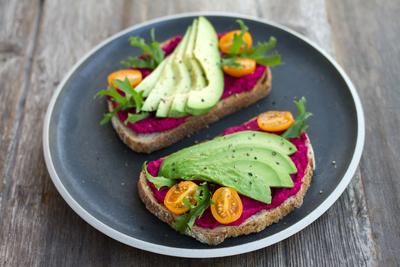 healthy plate of food, including bread, hummus, avocado, and tomato