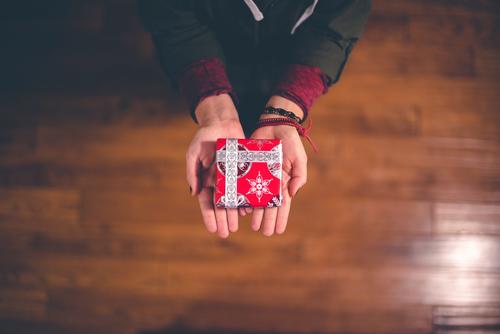 hands holding a small gift wrapped in red paper