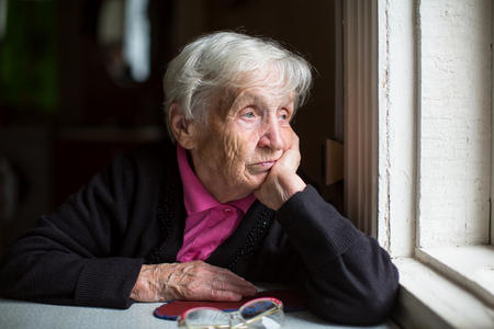 Elderly woman looking sadly out the window