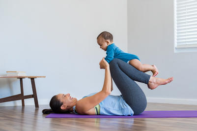 smiling mother doing yoga with cute baby