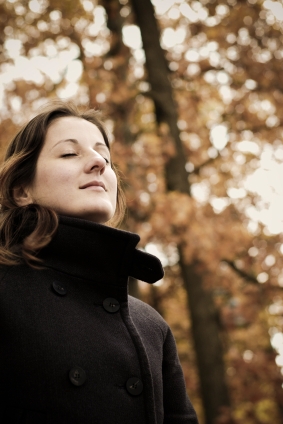 woman with eyes closed breathing deeply outdoors