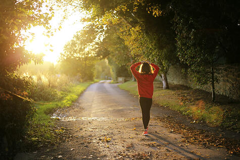 person walking in nature with their arms up