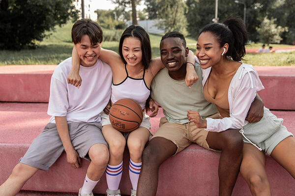 4 friends sharing a hug after a game of basketball