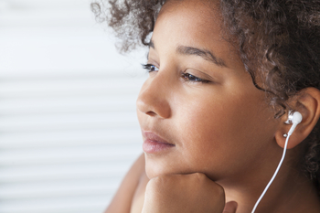 young girl listening to headphones and looking out the window