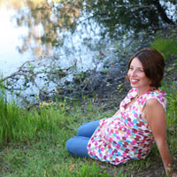 pregnant woman sitting near lake