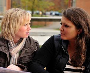 two women sitting next to one another, having a tense conversation