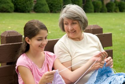 Older woman teaches young girl to knit.