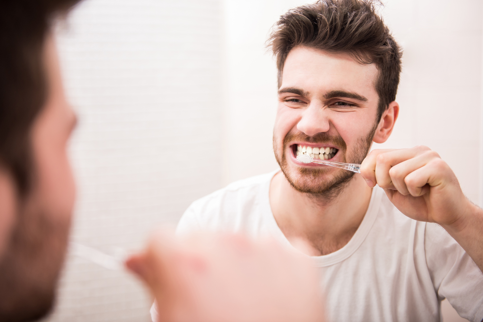 Man brushing his teeth and looking in the mirror