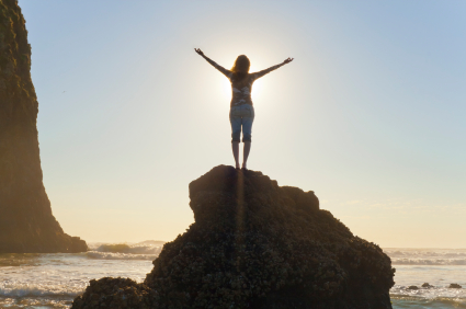 Woman standing on mountain with arms outstretched.