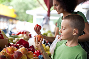 woman and young boy selecting apples at a market