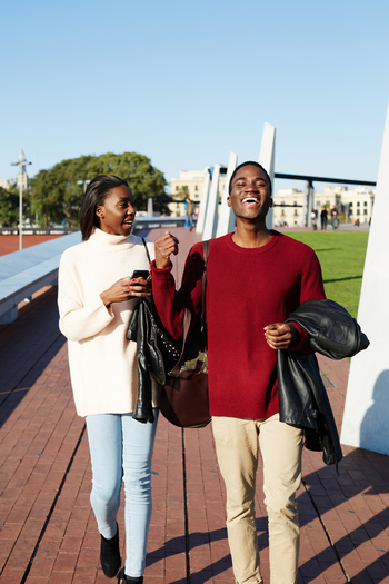 two college friends walking on campus and laughing together