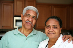senior couple in their kitchen, smiling at the camera