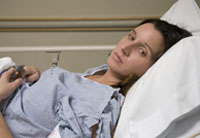 woman with pained expression lying in hospital bed