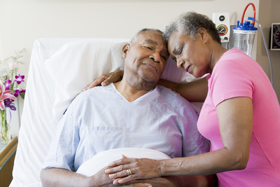 elderly patient in hospital bed with wife next to him