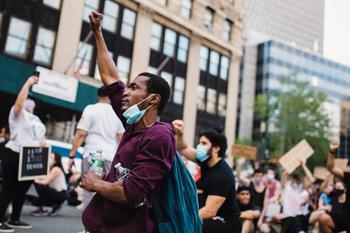 man holds fist in air at protest