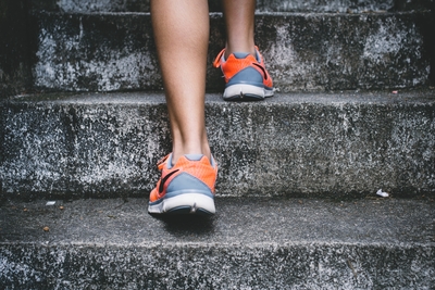 two feet with tennis shoes on climbing up stairs