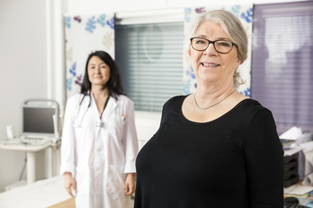 Smiling Senior Patient Standing With Doctor In Background