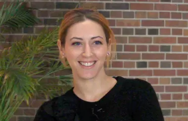 Kelly Mcgonical smiling at the camera in front of a brick wall