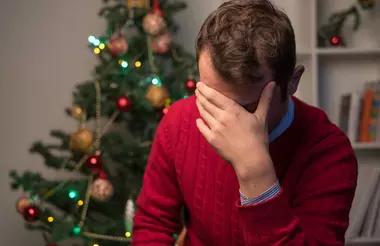 person holding their head in their hands in a red sweater