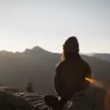 Person meditating alone watching the sun rise.