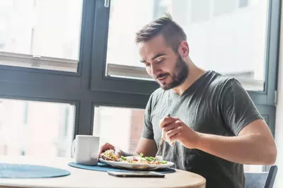 man eating breakfast by a window