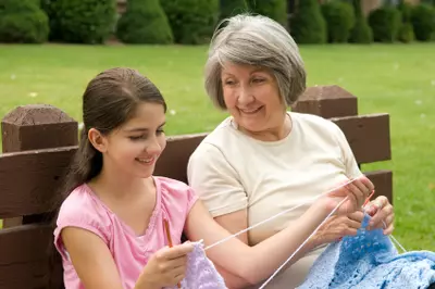 Older woman teaches young girl to knit.