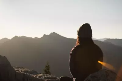 Woman sitting on top of mountain