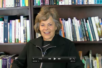 Ellen Langer smiling in front of a bookshelf